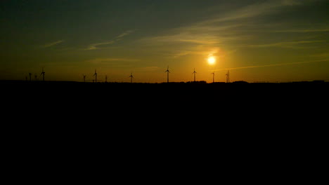 siluetas de turbinas eólicas giran en el horizonte al atardecer dorado en puck polonia