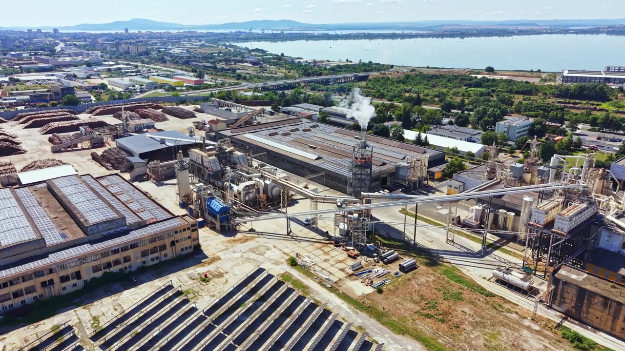 Area industriale vicino a un fiume con fabbriche, pannelli solari e sistemi di trasporto visibili