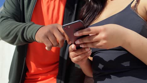 sección media de una pareja usando un teléfono móvil en un día soleado 4k