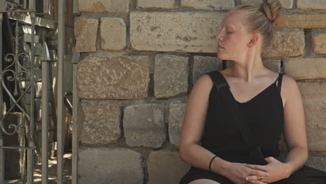 young female sits by wall in peaceful repose and quiet solitude reflection