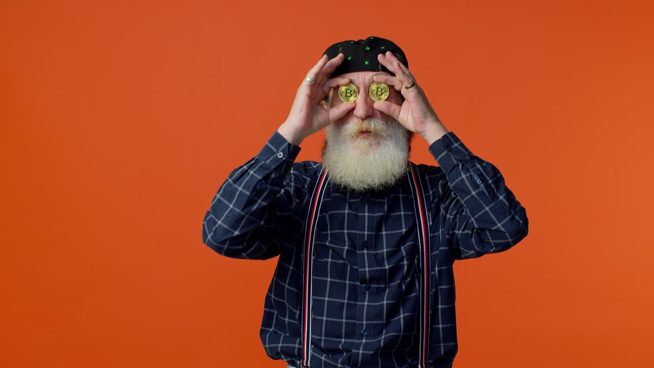viejo barbudo maduro hombre elegante que muestra bitcoins dorados, inversión en criptomonedas, tecnología minera