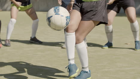 medium shot of an unrecognizable female football players' legs kicking soccer ball at the stadium