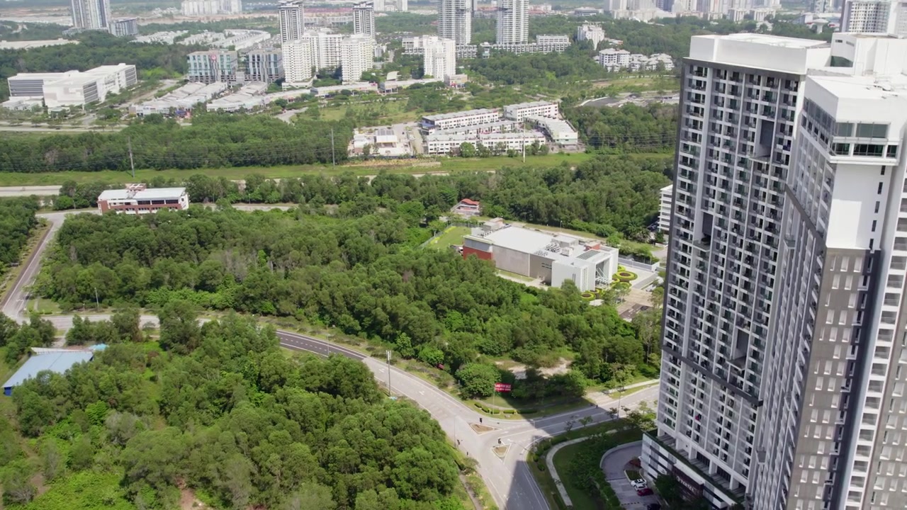 Tomada aérea cinematográfica de um edifício de apartamentos alto na Malásia, apresentando arquitetura moderna e arredores paisagísticos exuberantes.
