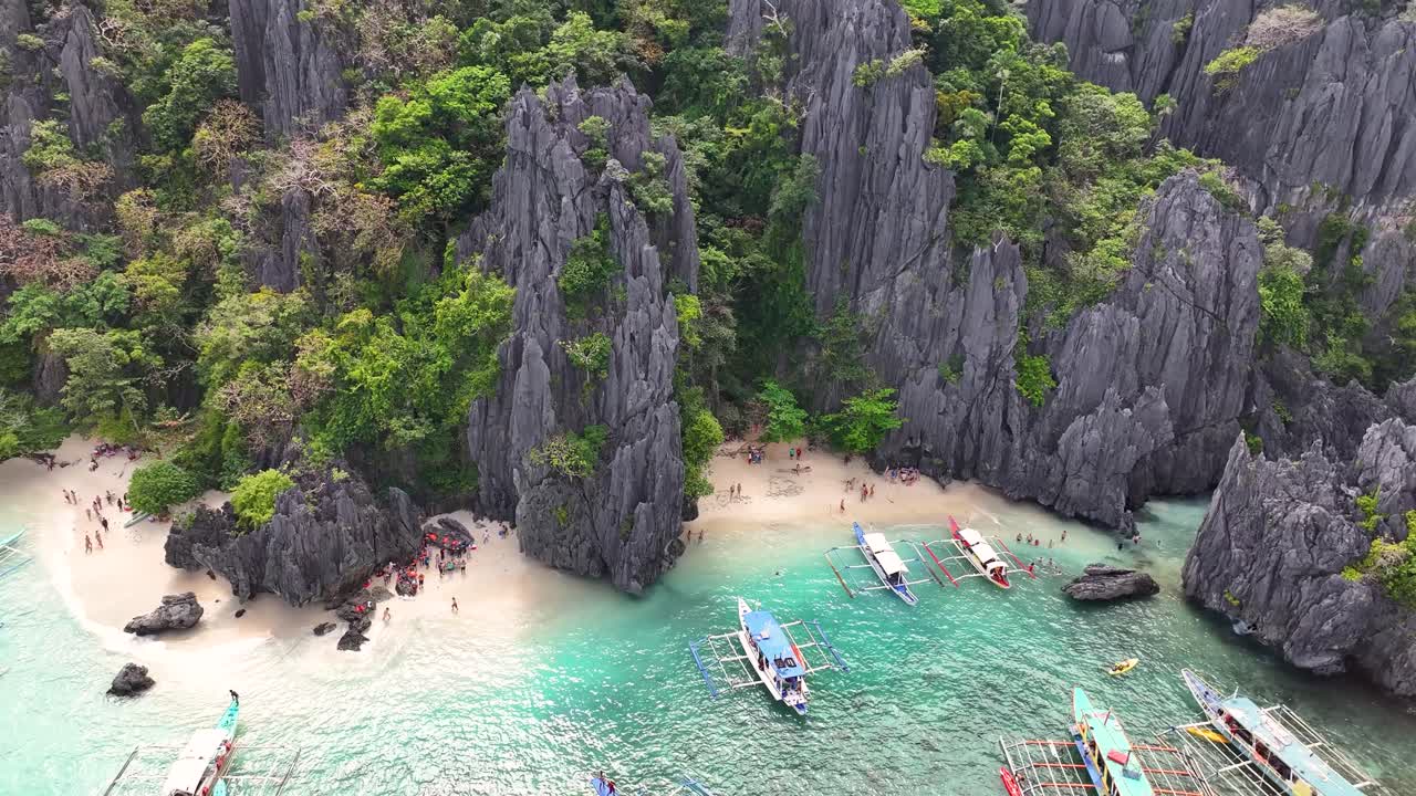 Playa El Nido con formaciones rocosas y barcos a lo largo de aguas turquesas, vista aérea