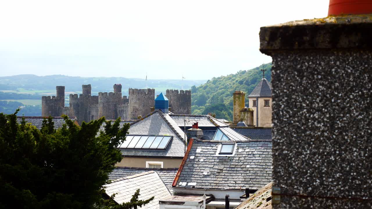 Residential homes rooftops inside Conwy castle townscape stone rampart walls dolly left reveal chimney