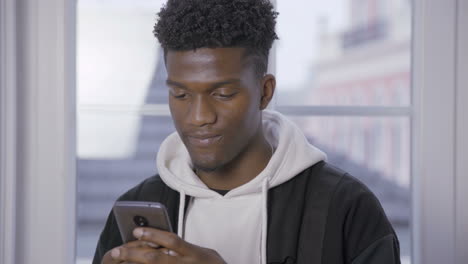 close-up of smiling young guy networking on mobile phone