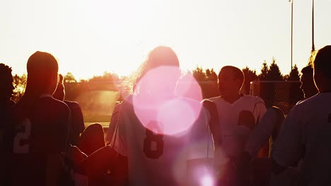 un equipo de fútbol sentado en un círculo jugando un juego divertido al atardecer