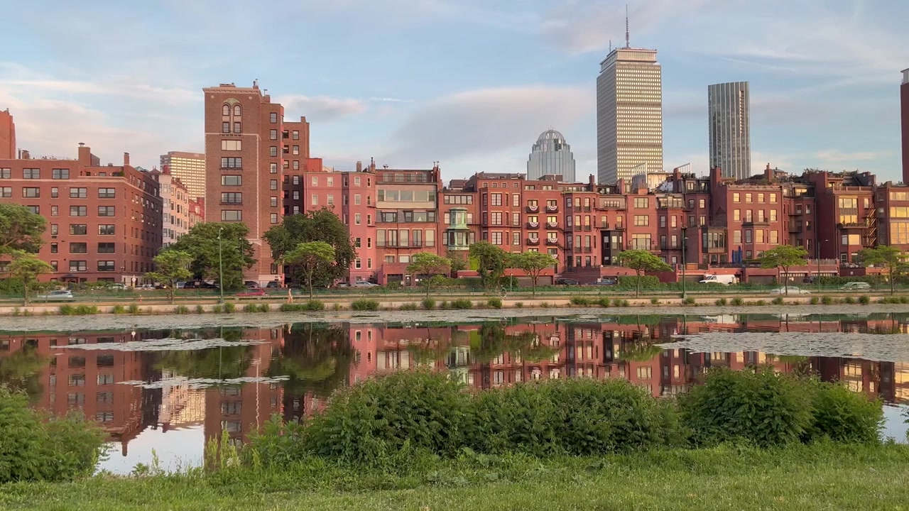Edifici storici Brownstone di Boston al tramonto riflessi nell'acqua calma dell'Esplanade del fiume Charles.