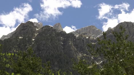 scenic alpine mountain range with clouds building in blue sky, pyrenees, sped up