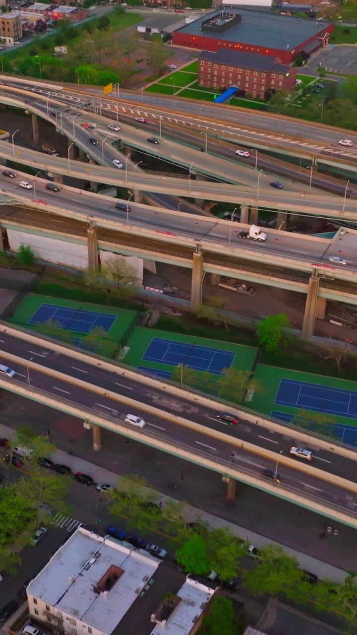 Low houses of New York and numerous parking lots. Complicated traffic system with cars moving on. Aerial perspective. Vertical video