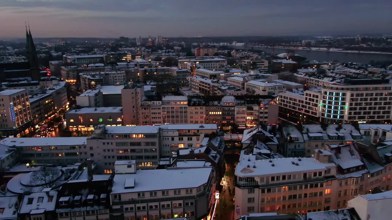 Aerial shot of Bonn city at night in winter. Snow covered city  at night. city lights at night, German city covered in snow, night drone shot of city at night covered in snow.
