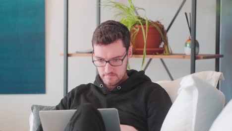 joven hipster sentado en el sofá con una laptop