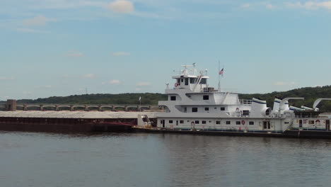 zoom out view of pusher boat moving a barge slowly through lock no