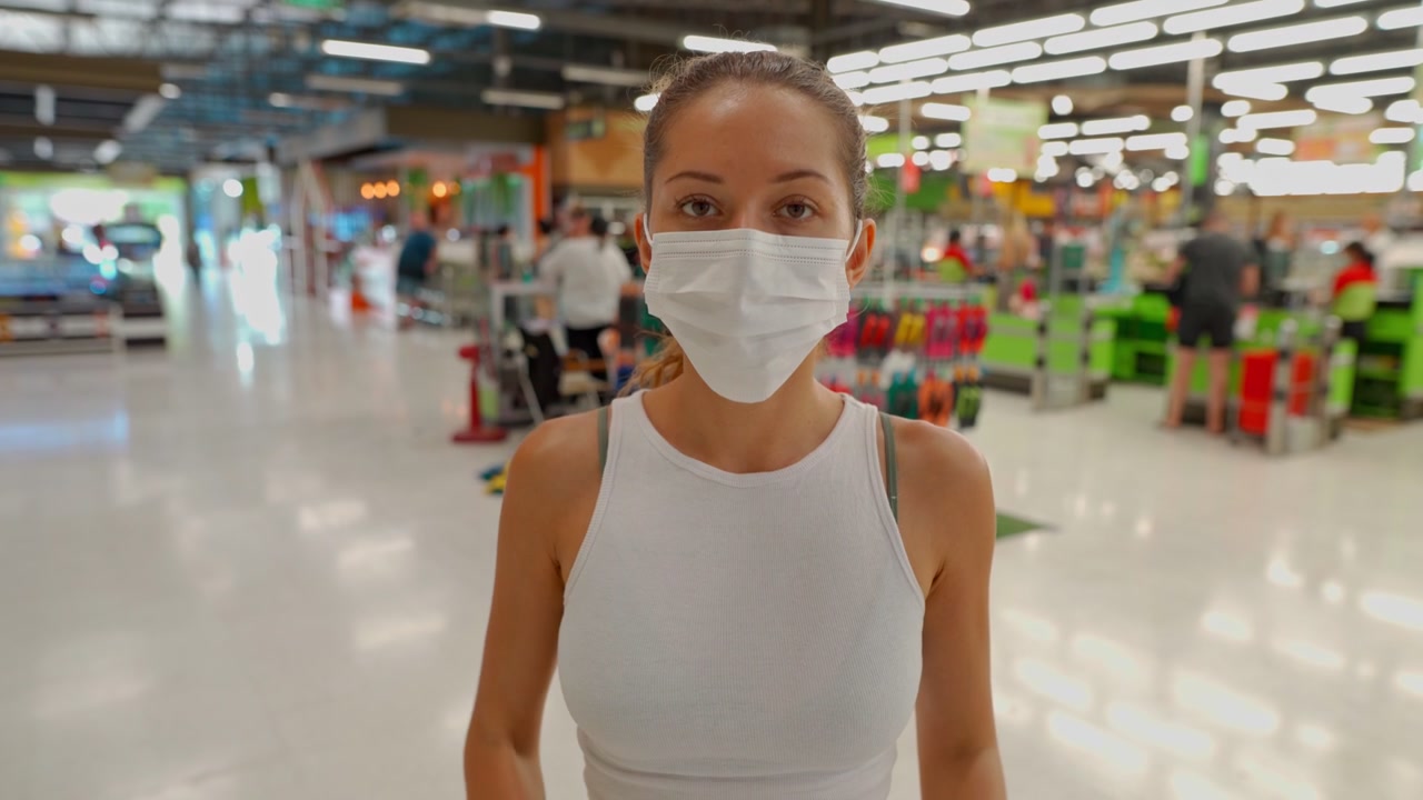 Young Woman Putting on a Face Mask in a Supermarket
