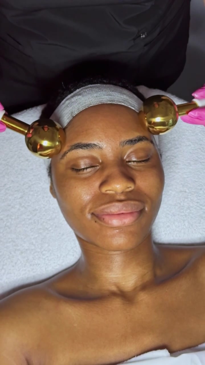 Femme recevant un soin du visage avec des outils en or dans un institut de beauté pendant la journée