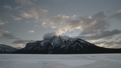 Imágenes-Cautivadoras-En-Timelapse-De-La-Tranquilidad-De-La-Madrugada-En-El-Lago-Minnewanka,-Alberta,-Con-La-Silueta-Del-Monte-Inglismaldie-Recortada-Contra-El-Cielo-Del-Amanecer