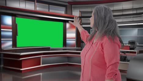 Indian-senior-female-journalist-pointing-towards-Green-screen