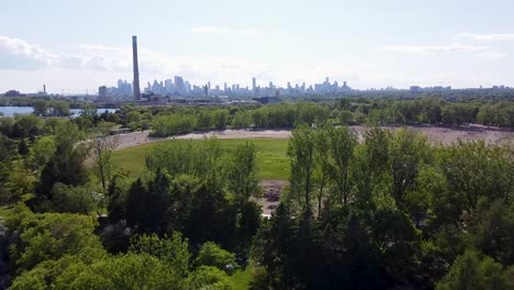 Sonnige-Luftaufnahme-Eines-Parks-Am-Ontariosee-Mit-Der-Skyline-Von-Toronto-In-Der-Ferne