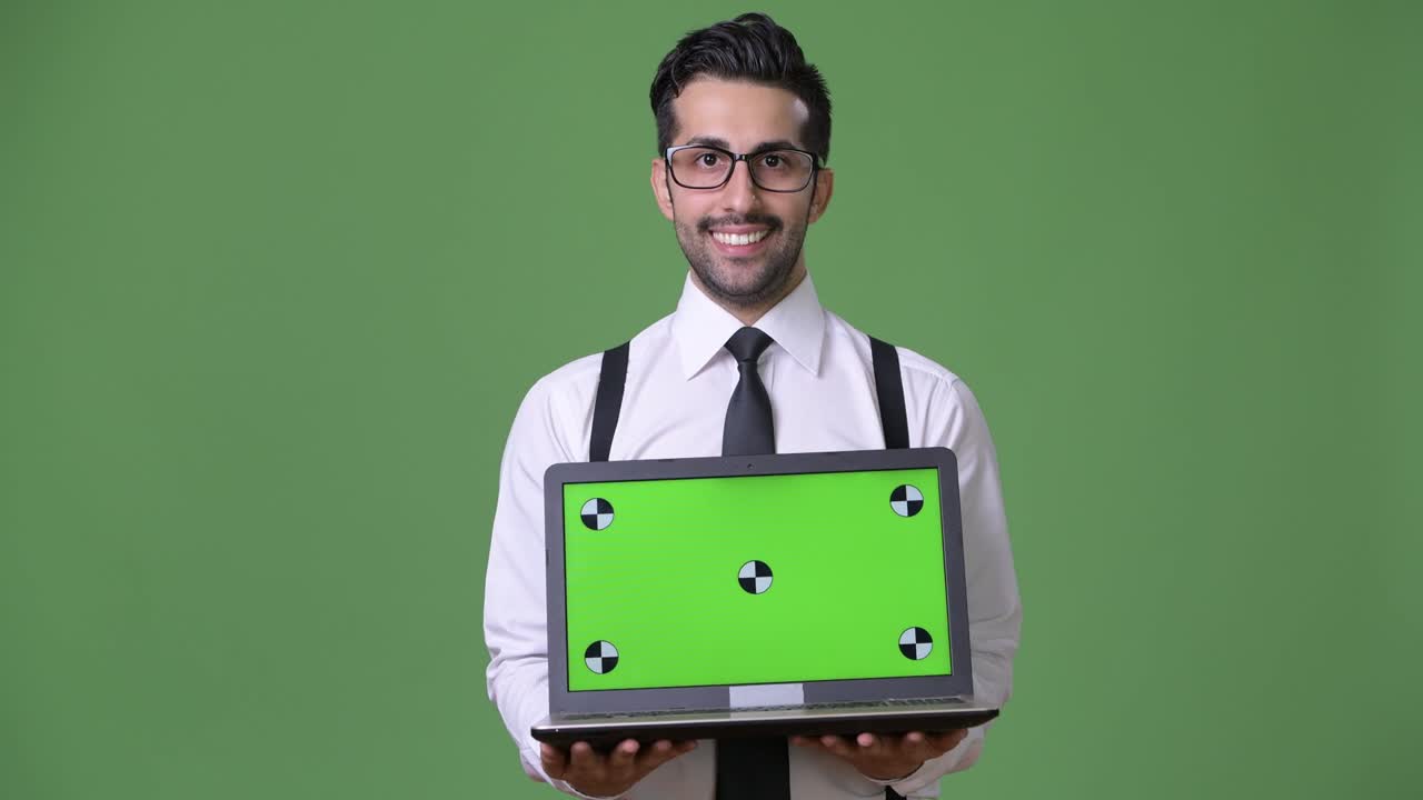 joven empresario persa barbudo y guapo contra un fondo verde