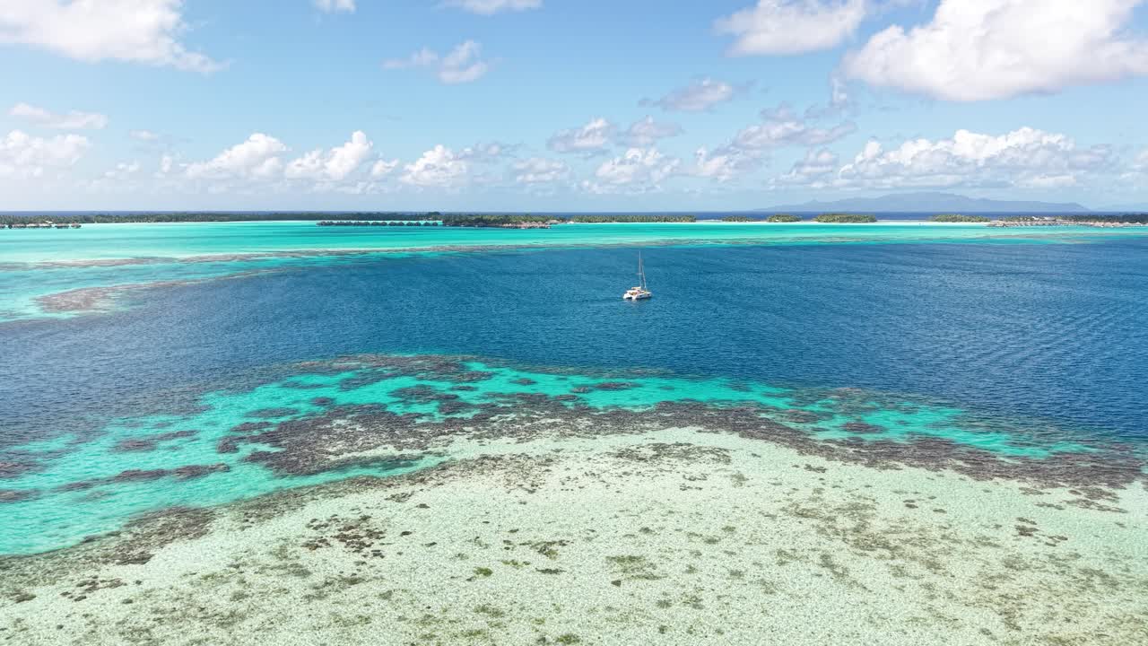 フランス領ポリネシア、ボラボラ島。島のラグーンに浮かぶボートとサンゴ礁のドローンショット。
