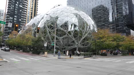 the spheres at amazon in seattle, featuring pedestrians and cars along lenora st and 7th ave. the modern glass domes sit amid tall skyscrapers, blending nature with urban architecture.