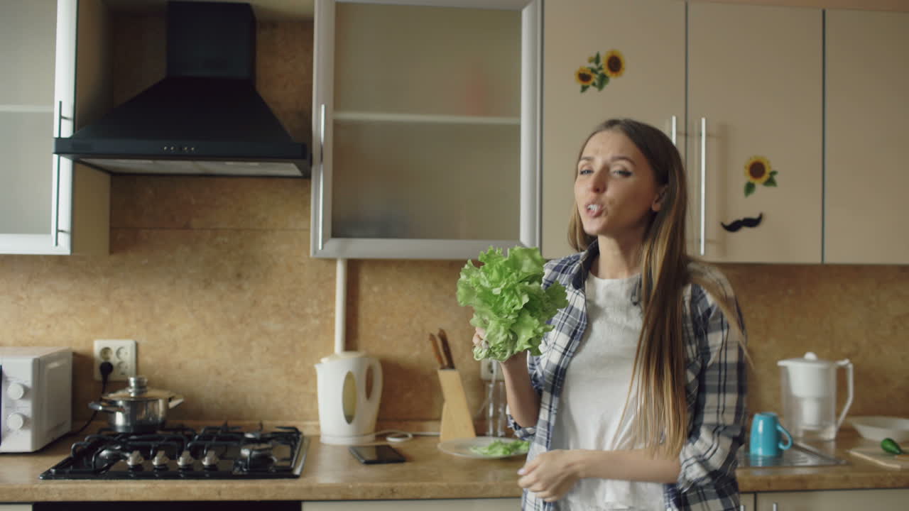 Donna che si diverte in cucina mangiando un'insalata