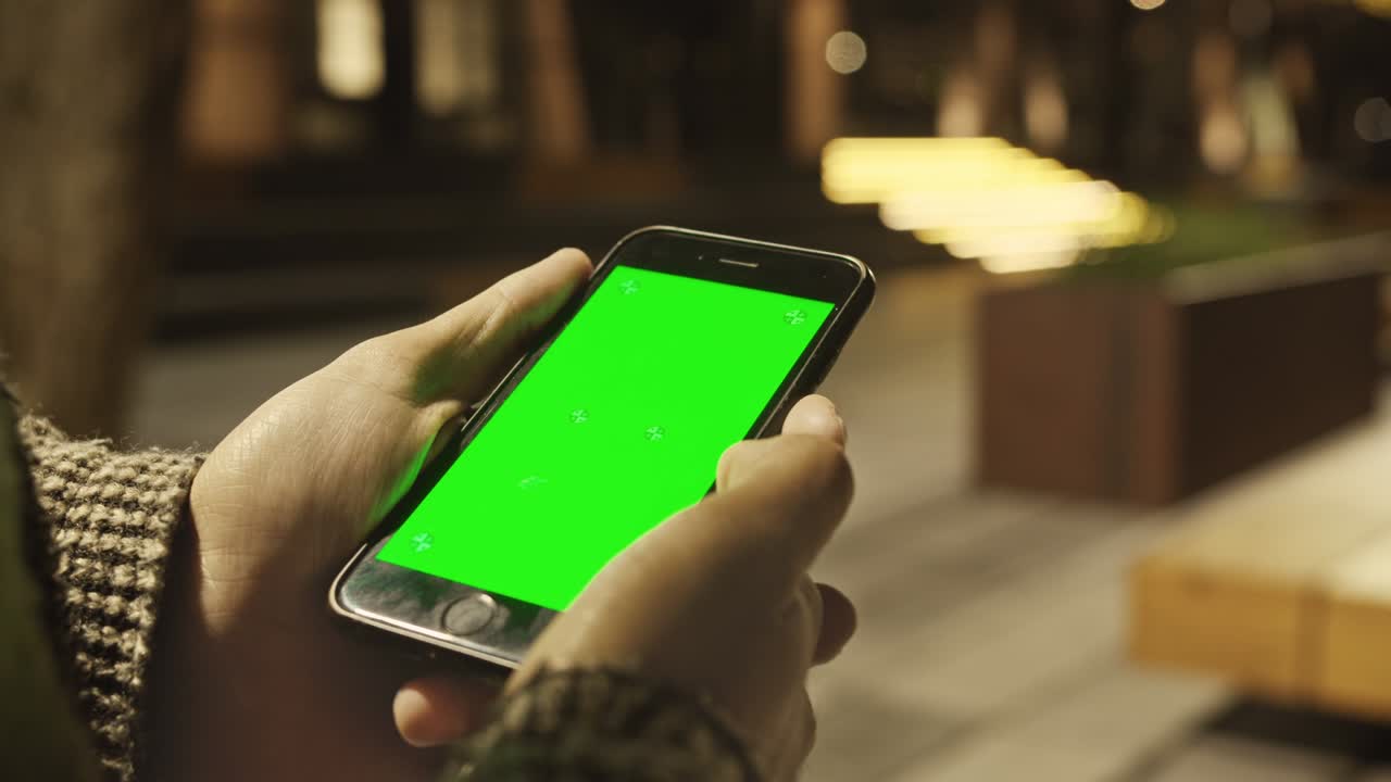 4K Close up of hand holding a smartphone with green screen display.