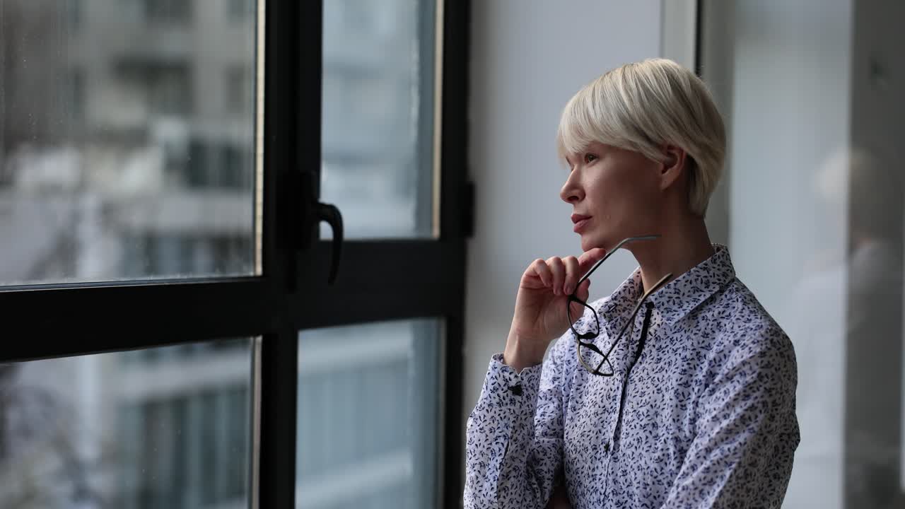 Woman looking out the window with eyeglasses