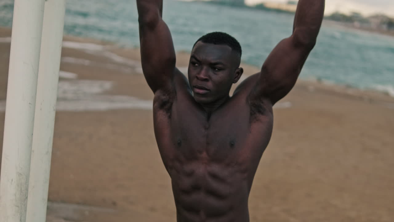 Muscular Black Man Doing Hanging Leg Raises on Beach
