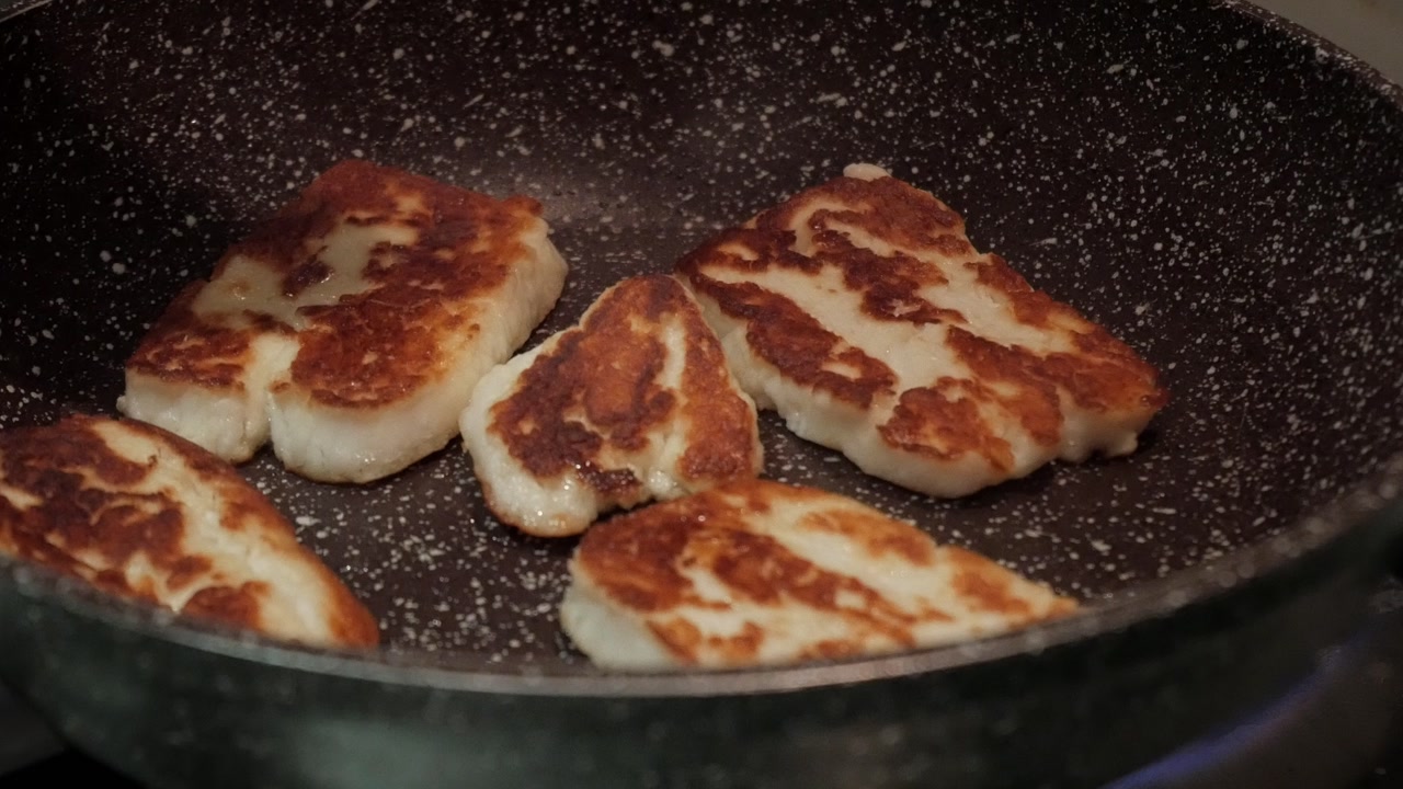 Grilling halloumi cheese in a hot pan, sizzling and golden brown