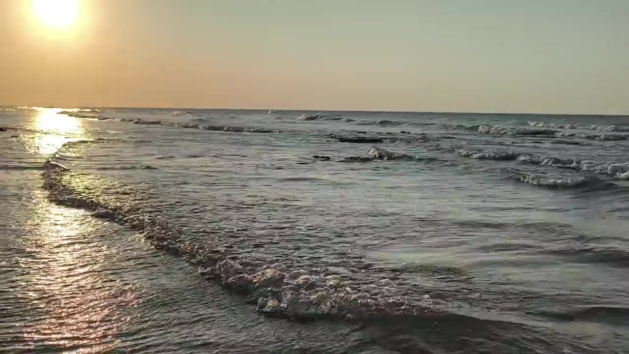 Dolci Onde dell'Oceano che si Infrangono su una Spiaggia Sabbiosa al Tramonto
