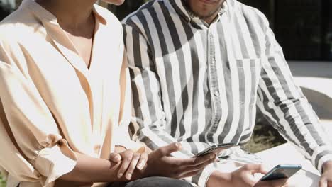 Serious-young-couple-looking-at-smartphone-on-street