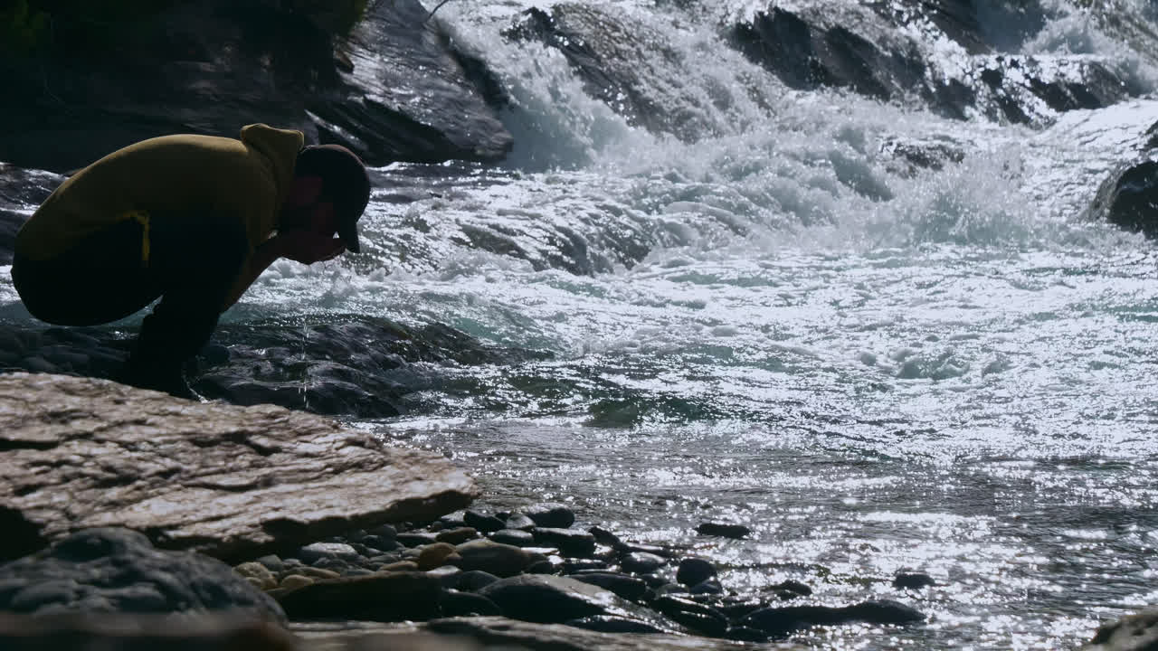 하이커는 자연스러운 강 하천에서 깨 ⁇ 한 순수한 신선한 물을 마시고, 중간 넓은  ⁇