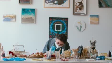artist creating resin art with dried flowers in a craft studio