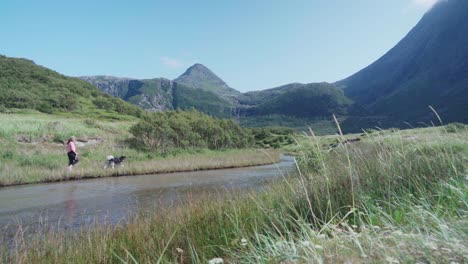 woman with dog walking in a grassy path in the bottom of donnamannen mountain - wide shot