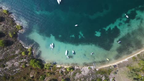 Overhead-Drohne-Clip-Einer-Kleinen-Tropischen-Inselbucht-Mit-Kristallblauem-Wasser-Und-Luxuriösen-Booten-In-Der-Gegend-Von-Vourvourou,-In-Nordgriechenland-Chalkidiki-In-4k