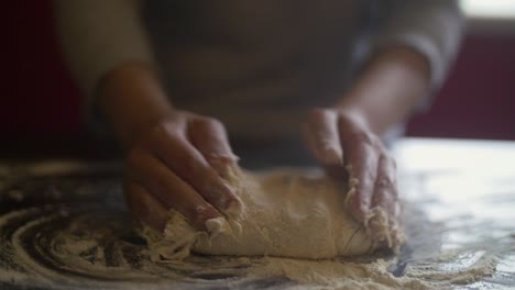 Woman's-hands-making-pizza-dough-on-a-marble-table-full-of-flour