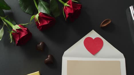 Corazón-De-Papel-En-Sobre-Y-Rosas-Con-Copas-De-Champán-Sobre-Fondo-Negro-En-El-Día-De-San-Valentín