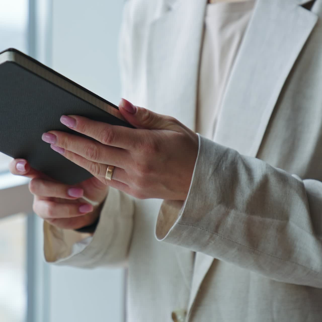 Female hands holding a paper notebook in black cover. Unrecognizable woman opens the book. Close up