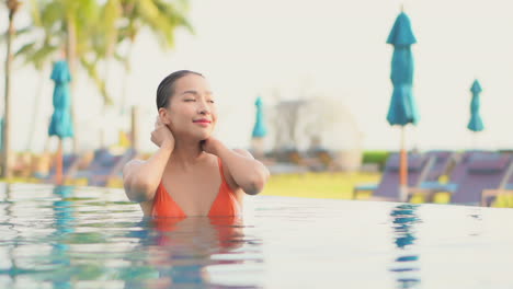 Pequeña-Mujer-Asiática-Mojada-Y-Sexy-En-La-Piscina-Acariciando-Su-Cabello,-Cámara-Lenta