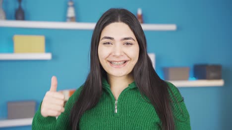 Young-woman-with-braces-looks-at-camera,-makes-okay-sign-and-smiles.