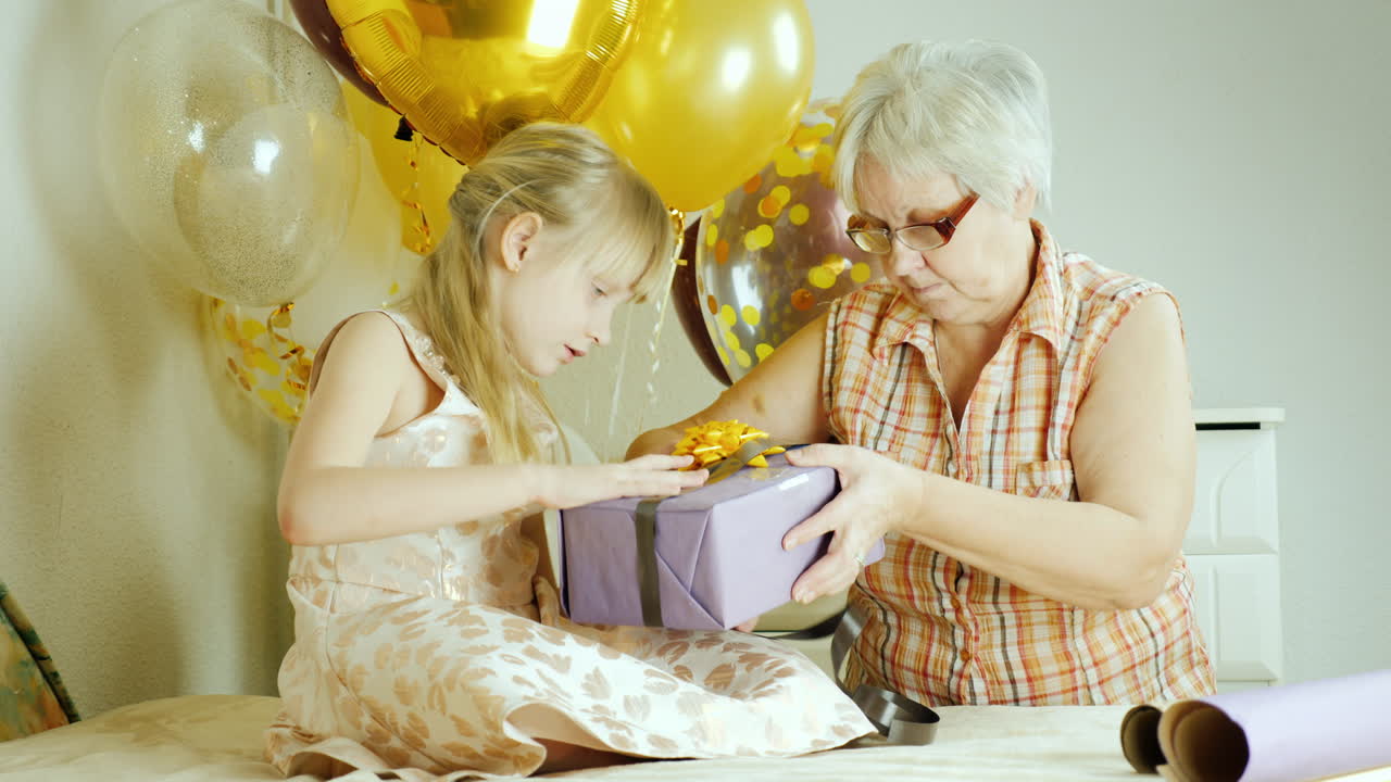empacando regalos para cumpleaños una anciana con una niña está empacando un regalo juntos