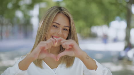 girl showing hand heart and smiling at camera