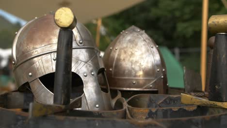 Two-viking-helmets-and-swords-on-showcase-on-outdoor-fair-on-sunny-summer-day,-right-circular-slider-shot