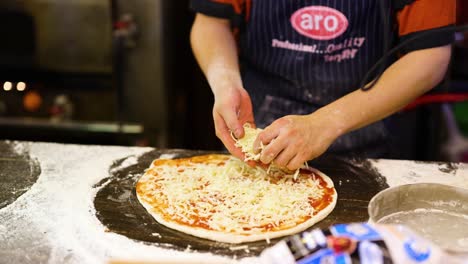 chef preparing pizza with cheese and tomato sauce