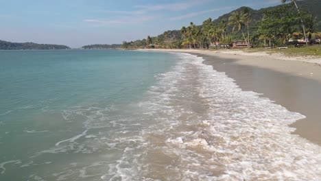 Drohne,-Die-Meereswellen-Am-Leeren-Weißen-Sandstrand-Einfängt,-Meereswelle,-Die-Zum-Küstenstrand-Reist,-Palmen,-Die-Von-Drohnen-Eingefangen-Werden,-Die-Sich-Am-Küstenstrand-Des-Ozeans-Bewegen