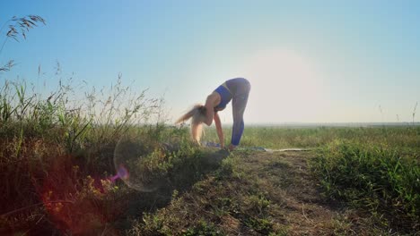 woman practicing yoga in a field at sunrise