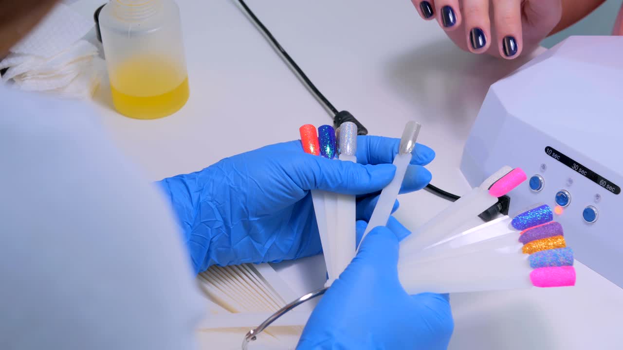 el técnico de uñas muestra la paleta de colores de los servicios de uñas en el salón de belleza.