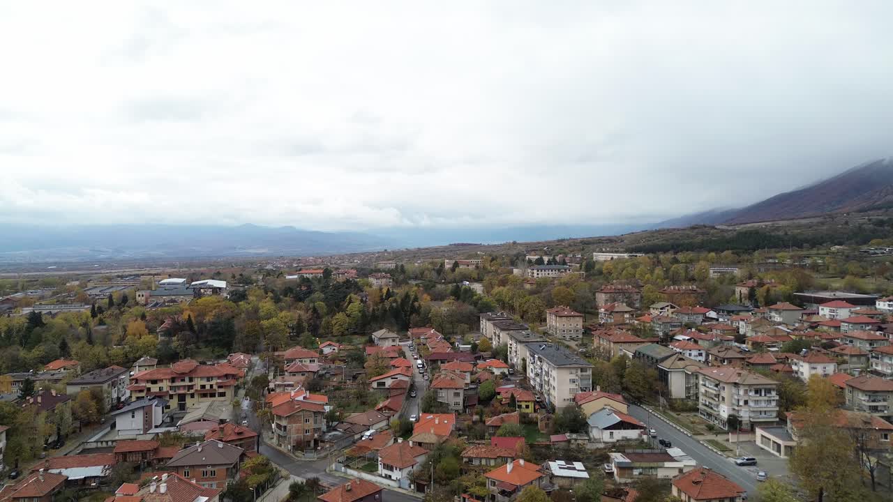 A beautiful aerial view of Sopot, a charming Bulgarian town at the foot of the Balkan Mountains, showcasing its balkan architecture and scenic surroundings, on an overcast autumn day, looking west