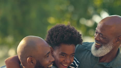 Porträt-Einer-Liebevollen-Männlichen-Mehrgenerationenfamilie,-Die-Draußen-Im-Gartenpark-Oder-Auf-Dem-Land-Steht